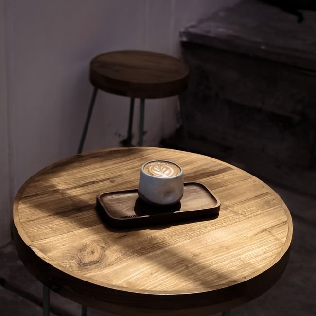 Cappuccino avec dessin dans la mousse posé sur une table en bois.