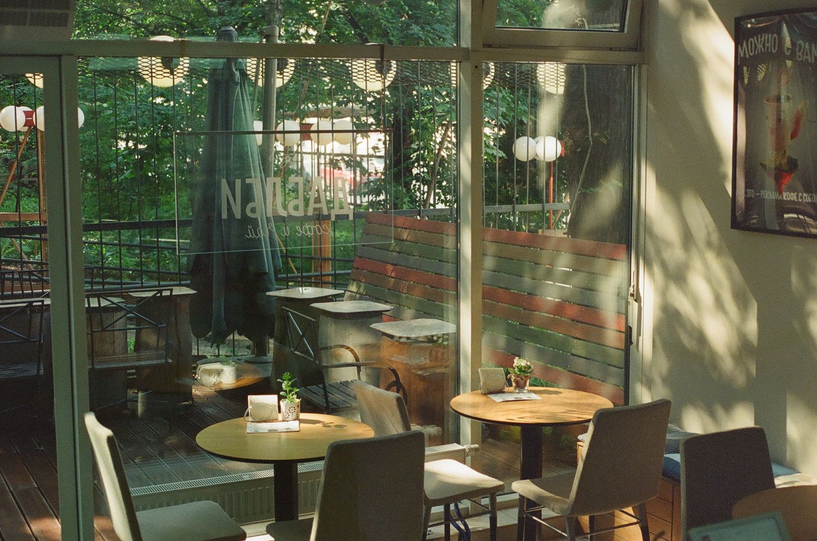Intérieur lumineux du café avec grandes fenêtres et tables en bois.