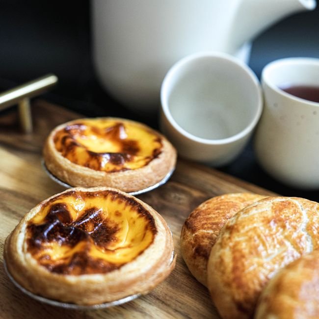 Gros plan d'un pastel de nata montrant la crème dorée et la pâte feuilletée.