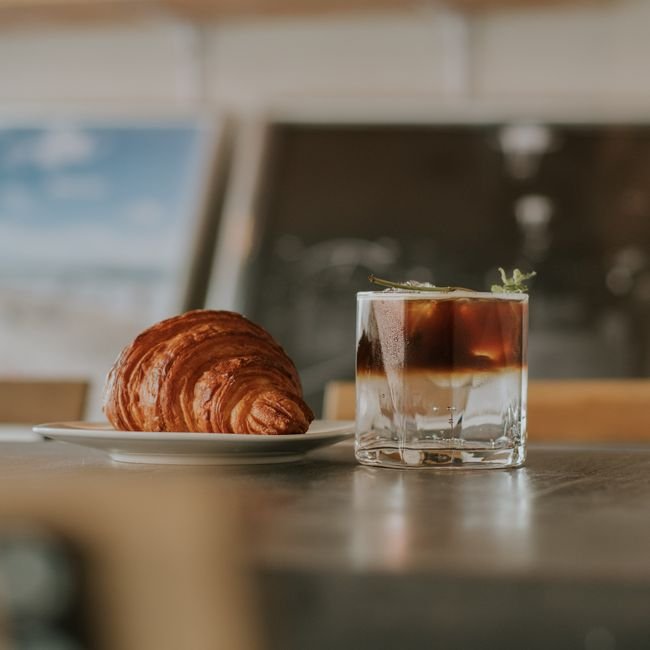 Assiette de viennoiseries et pâtisseries dans un café lumineux.
